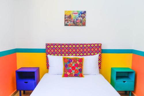 une chambre colorée avec un lit et deux tables de nuit dans l'établissement Casa Paraiso, à Santa Cruz Huatulco