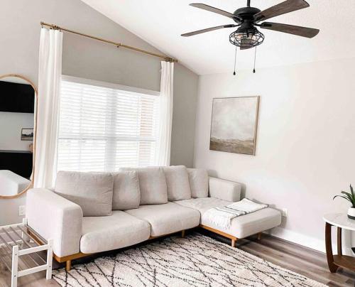 a white couch in a living room with a ceiling fan at Cottage Marhome North - 10 min from beach & historic downtown in Saint Augustine