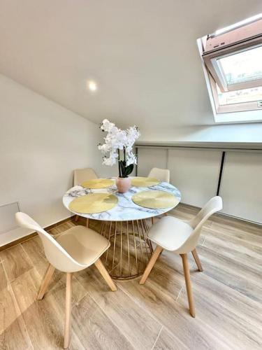 une table avec des chaises et un vase de fleurs dessus dans l'établissement Appartement climatisé - 2min plage-tram-restaurant, à Nice