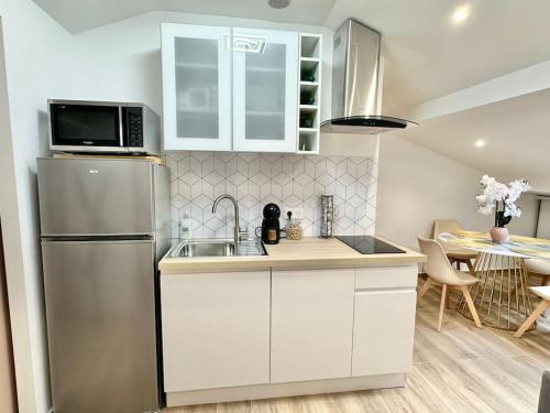  La cuisine est équipée de placards blancs et d'un réfrigérateur. dans l'établissement Appartement climatisé - 2min plage-tram-restaurant, à Nice