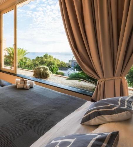 a bedroom with a large window with a view of the ocean at La Risacca Relais in Belvedere Marittimo