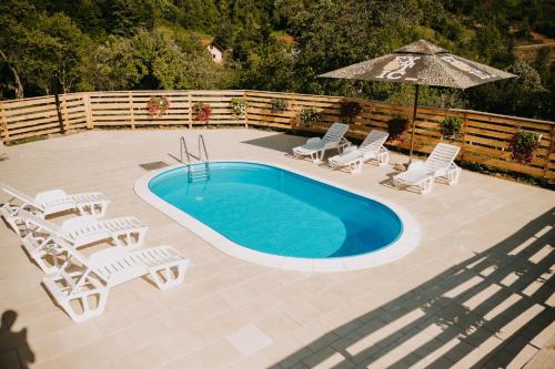 einen Pool mit Stühlen und einem Sonnenschirm in der Unterkunft Vidovo Domacinstvo in Banja Luka