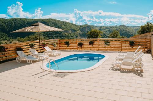 a swimming pool with chairs and an umbrella at Vidovo Domacinstvo in Banja Luka