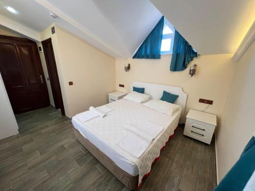 a bedroom with a bed with white sheets and blue curtains at Kaliptus Hotel in Kemer