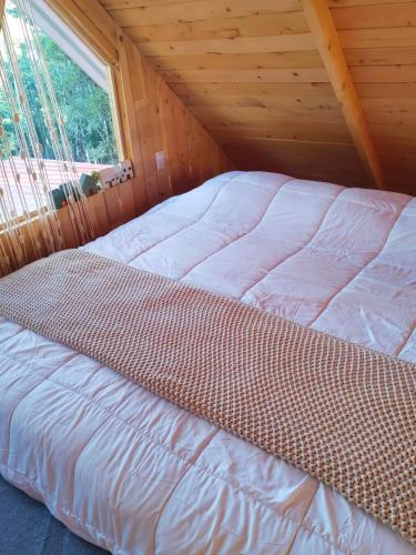 a bed in a wooden cabin with a window at Cabaña Lugar de Paz in División