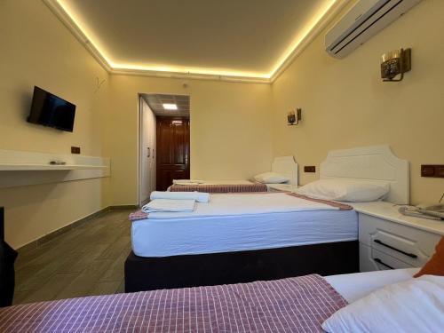 a hotel room with three beds and a television at Kaliptus Hotel in Kemer
