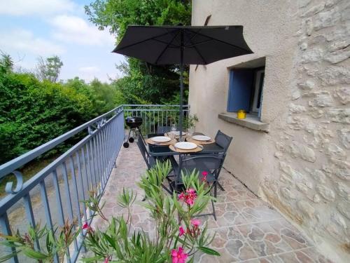 une table avec un parasol sur un balcon dans l'établissement Gîte coteaux de Montcuq - 4 personnes, à Belvèze