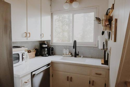 Una cocina blanca con fregadero y ventana. en A-Frame Cabin in The Woods, Close to Shops!, en Lake Arrowhead