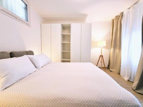 a white bedroom with a bed and a window at Sanremo Suite Apartment in Sanremo