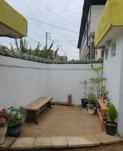 a patio with two wooden benches and potted plants at Hanok Stay Ohneul in Gyeongju