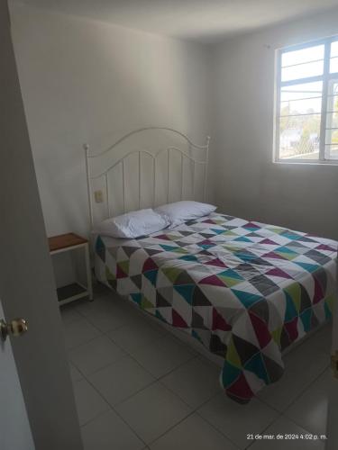 a bed with a colorful comforter in a bedroom at hermoso departamento in Ocotlán