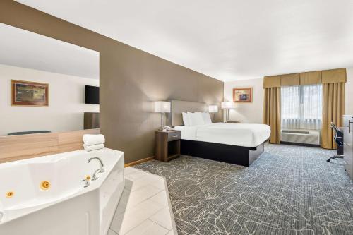 マディソンにあるBest Western West Towne Suitesのベッドとバスタブ付きのホテルルームです。