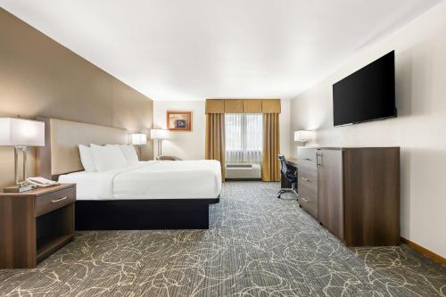 a hotel room with a bed and a flat screen tv at Best Western West Towne Suites in Madison