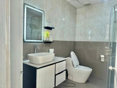 a bathroom with a sink and a toilet and a mirror at Nice Oasky Apartment Ocean Key 502 in Vung Tau