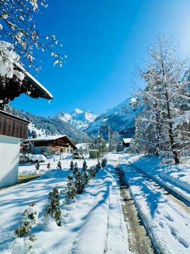 a snow covered street with trees and mountains at Amazing Modern & Great equipped Jacuzzi Apartment in Kandersteg