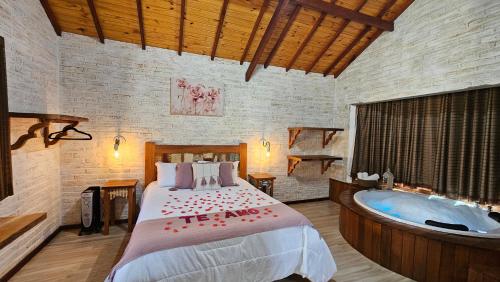 um quarto com uma cama e uma banheira em Chalé Gosto da Roça em Monte Verde