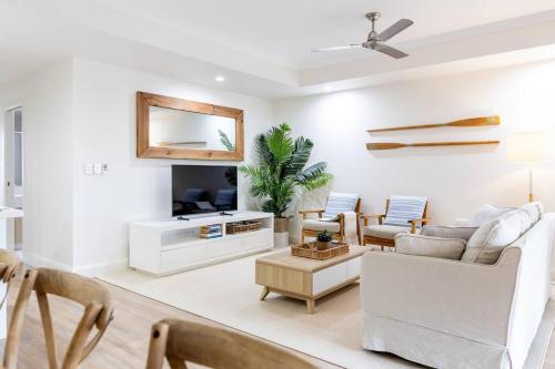 a living room with white furniture and a mirror at Charming Riverside Noosa gem in Noosaville