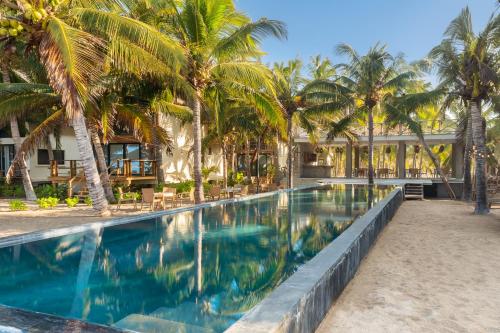 ein Swimmingpool vor einem Resort mit Palmen in der Unterkunft Casa Vela Palafito en playa con alberca in La Manzanilla