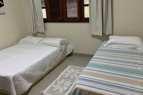 two twin beds in a room with a window at CasaMares Macapá - Praia de Macapá in Macapá