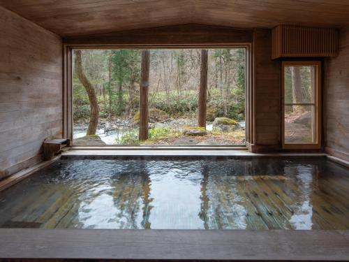 高山市にある日本の宿　ひだ高山　倭乃里の大きな窓と水のプールが備わる客室です。