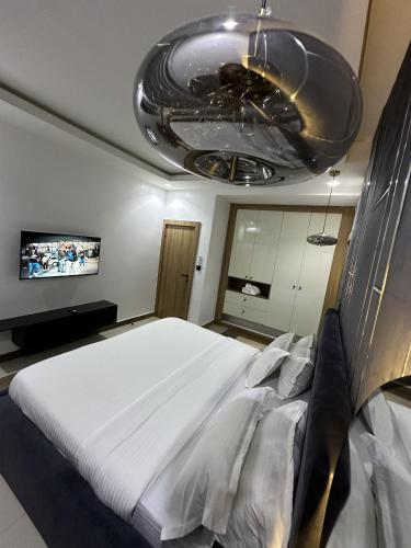 a bedroom with a large bed and a chandelier at Volux Luxury Classic Apartment Wuye, Utako Abuja in Abuja