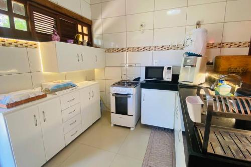 a kitchen with white cabinets and a stove top oven at CasaMares Macapá - Praia de Macapá in Macapá