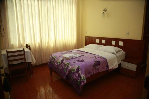 a bedroom with a bed with a purple comforter at Hotel Mi Estrella in Chimbote