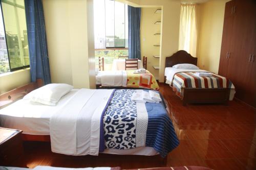 a hotel room with three beds and a window at Hotel Mi Estrella in Chimbote