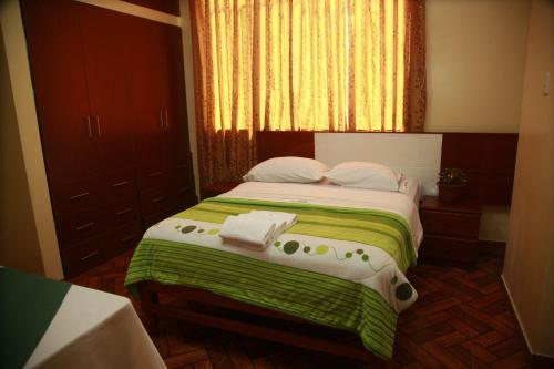 a bedroom with a large bed with a green blanket at Hotel Mi Estrella in Chimbote