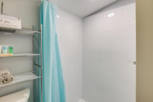 a bathroom with a shower with a blue shower curtain at Pet-Friendly Waterfront Cottage On-Site Bunkhouse in East Wakefield