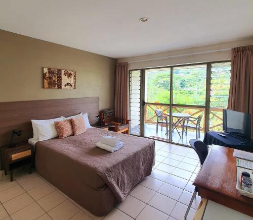 sypialnia z łóżkiem i telewizorem oraz balkonem w obiekcie Vaea Hotel Samoa w mieście Apia