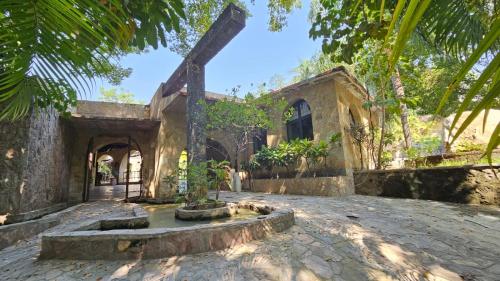 an old stone house with a courtyard and trees at Rancho Agua Salada in Alpuyeca