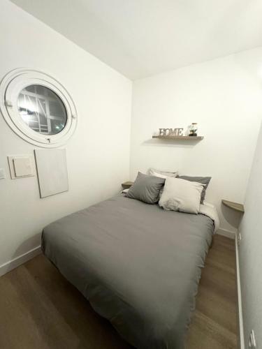 un lit dans une chambre blanche avec une fenêtre dans l'établissement Appartemment vue mer et piscine, à Villeneuve-Loubet