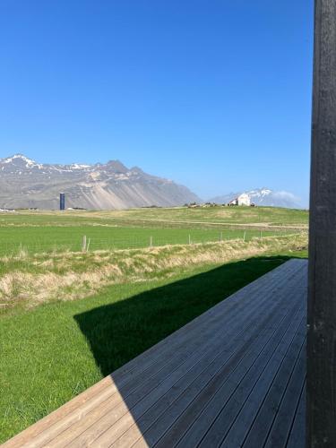 a wooden deck with a field and mountains in the background at REY Stays - Small & Cozy Studio in Höfn