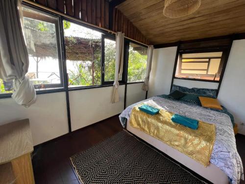 a bedroom with a bed in a small room with windows at Te Ava Rahi Lodge in Katiro
