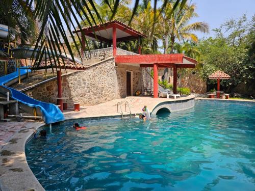 a pool with a slide and people in the water at Rancho Agua Salada in Alpuyeca