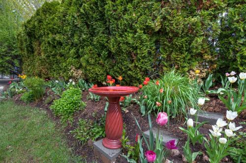 a red bird bath in a garden with flowers at The Gibson Mansion Bed and Breakfast in Missoula
