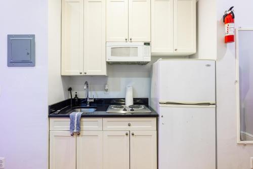 a kitchen with white cabinets and a white refrigerator at Studios in New York in New York