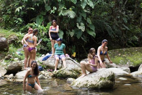 a group of women sitting on rocks in a river at Camelia Hostel in San Carlos