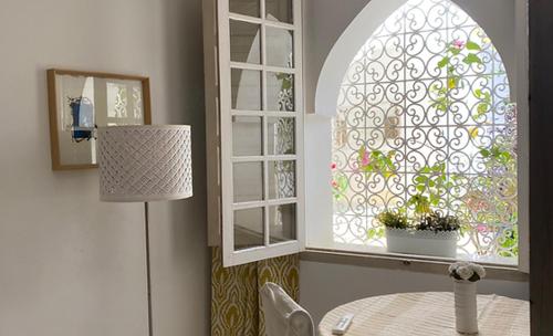 a room with a table and a window with a potted plant at Grande demeure de charme in Asilah