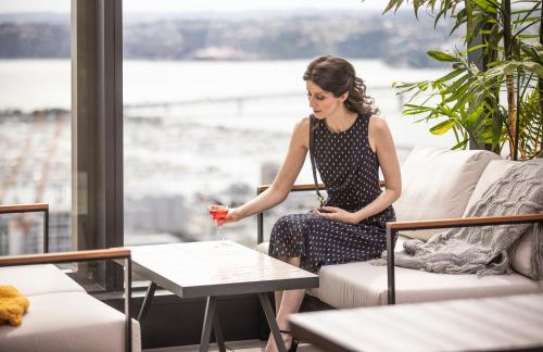 a woman sitting on a couch holding a glass of wine at voco Auckland City Centre by IHG in Auckland