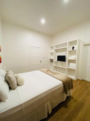 a white bedroom with a bed and white shelves at Casa Nefertari I in Flores