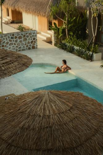 a woman sitting in a swimming pool at a resort at Boni Beach Lombok Boutique Hotel & Villas in Selong Belanak