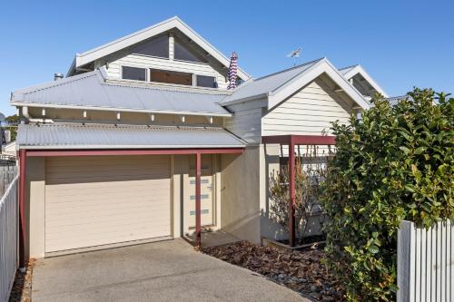 a white house with a garage and a fence at Townhouse on King in Queenscliff