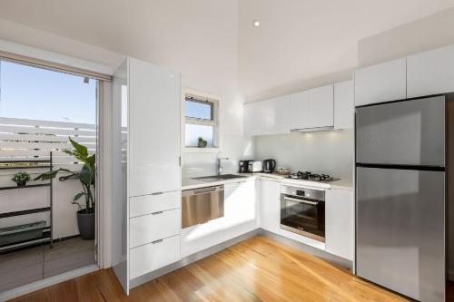 a kitchen with white cabinets and a large window at Townhouse on King in Queenscliff