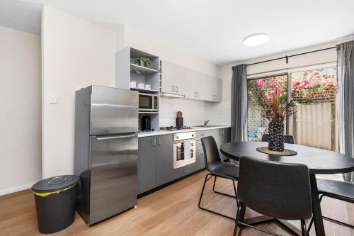 a kitchen with a table and a stainless steel refrigerator at 4 Cute Cunningham Close To Subiaco - Sleeps 4 in Perth