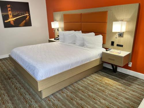 a hotel room with a large bed with white sheets at Presidio Parkway Inn in San Francisco
