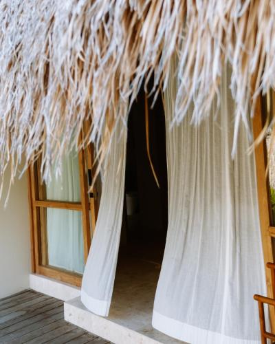 a thatch roofed hut with a window at Boni Beach Lombok Boutique Hotel & Villas in Selong Belanak