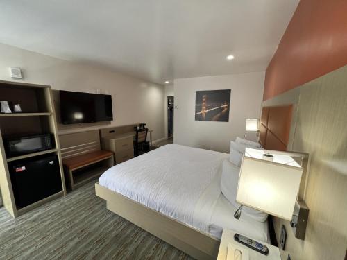 a hotel room with a bed and a flat screen tv at Presidio Parkway Inn in San Francisco