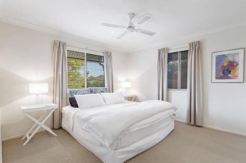 una camera da letto bianca con un letto e una finestra di Cottage on Kent a Toowoomba
